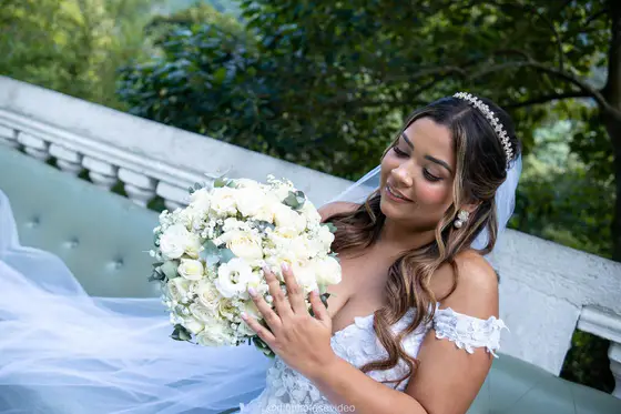 Noiva sorrindo com o buquê de rosas brancas