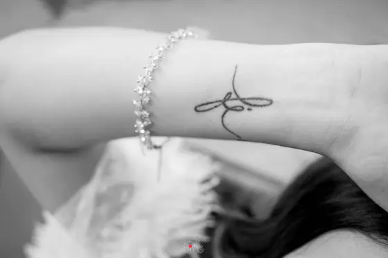 Em preto e branco, detalhe da pulseira e da tatuagem no pulso da noiva