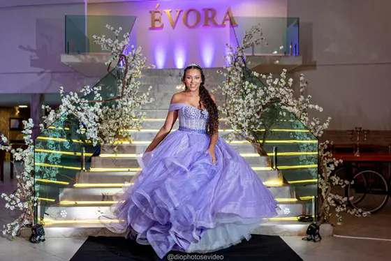Debutante de vestido lilás na escadaria decorada com flores